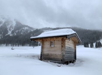 Built structure on snow covered field against mountain