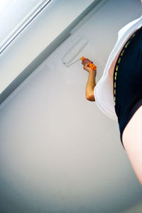 Low angle view of woman painting ceiling at home
