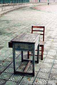 Empty bench on sidewalk in park