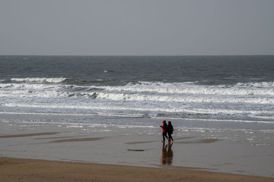 Rear view of man standing at beach against clear sky