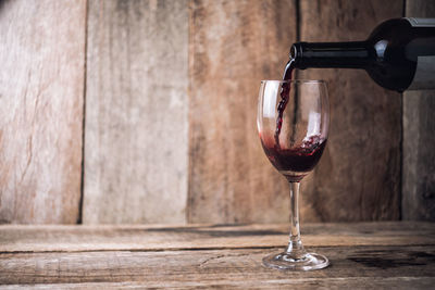 Close-up of wine pouting in wineglass on wooden table