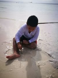 Boy playing on sea shore at beach during sunny day