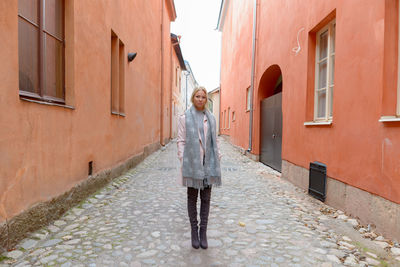 Full length woman standing on footpath amidst buildings