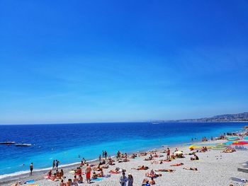 Group of people on beach against blue sky