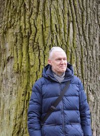 Portrait of woman standing on tree trunk