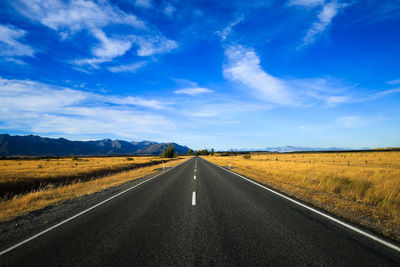 Road amidst field against sky