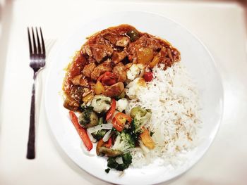 High angle view of rice with meat and vegetable served on table