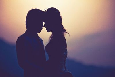 Silhouette couple standing face to face during sunset