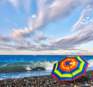 Deck chairs on beach against sky