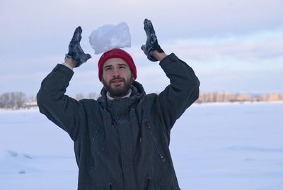 Portrait of young man balancing ice on head outdoors