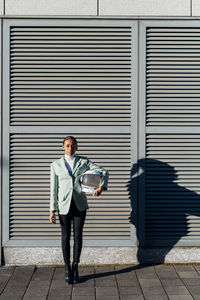 Businesswoman with astronaut helmet in front of striped wall