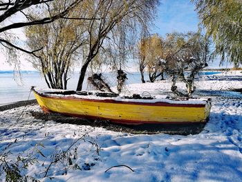 Boat moored in lake against sky during winter