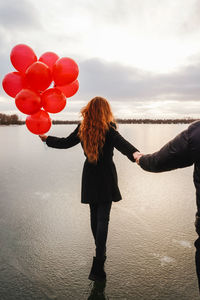 Rear view of woman standing on balloon against sky