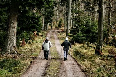 Rear view of two people walking on countryside pathway