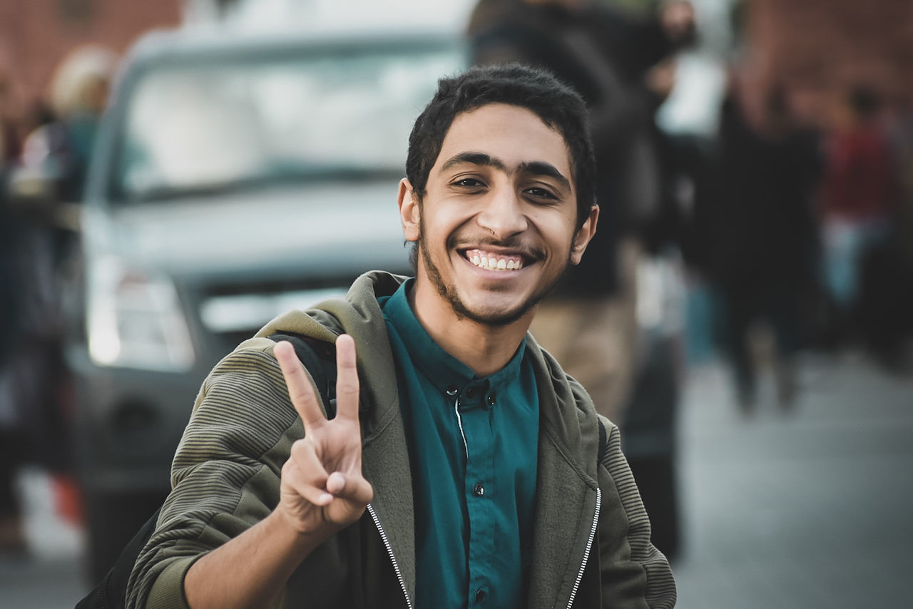 smiling, portrait, young adult, happiness, one person, looking at camera, young men, front view, focus on foreground, real people, lifestyles, transportation, mode of transportation, incidental people, toothy smile, teeth, men, leisure activity, casual clothing, outdoors