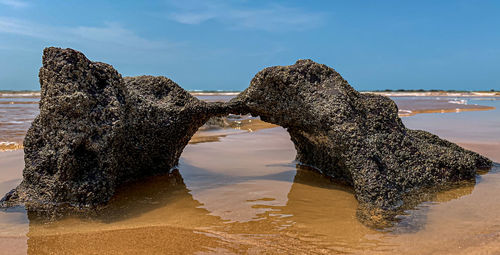 Rock formation on beach against sky