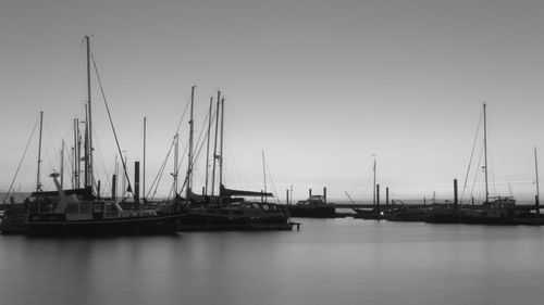 Sailboats moored at harbor against sky