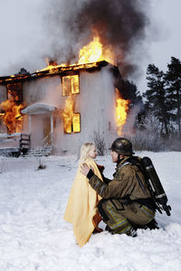 Fireman holding rescued girl, burning building in background