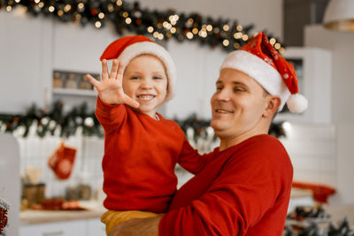 Portrait of smiling young woman standing against christmas tree
