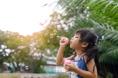 Girl blowing bubbles by pond