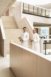 Doctors walking in corridor by railing at hospital