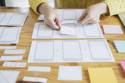 High angle view of woman hand on paper at table