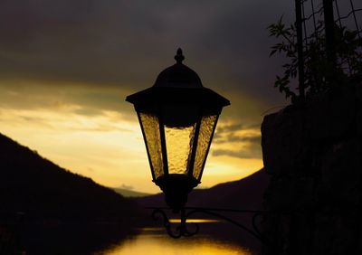 Silhouette lamp against sky during sunset