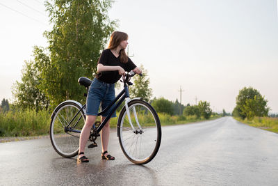 Woman with bicycle standing on road