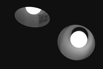 Low angle view of illuminated lamp against black background