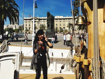 Full length of woman photographing with city in background