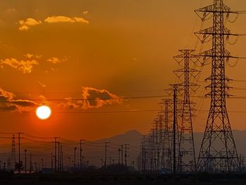 Silhouette of electricity pylon against sky during sunset