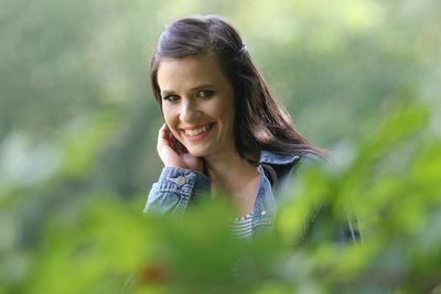 Portrait of smiling young woman against trees