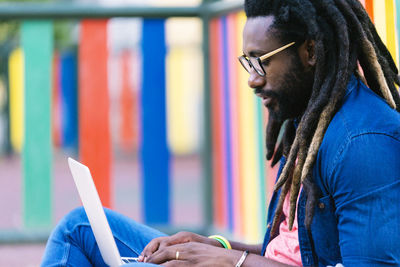 Side view of young man using laptop in city