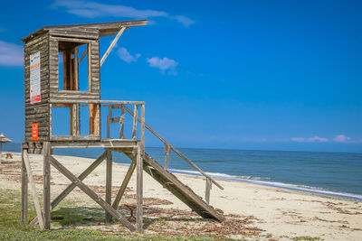Lifeguard hut on beach against blue sky