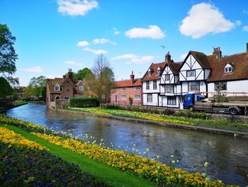 Scenic view of river by buildings against sky