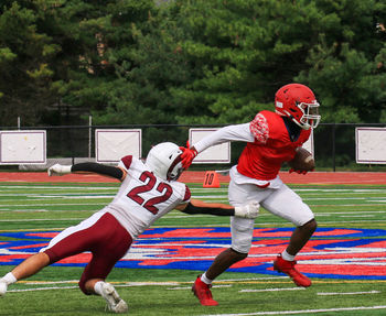 A football player breaking the tackle of the defender during a game and running away.