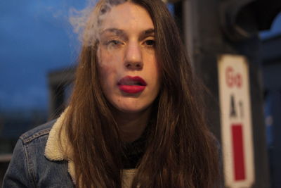 Close-up portrait of young woman emitting smoke