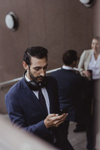 Businessman using mobile phone while coworkers talking in background