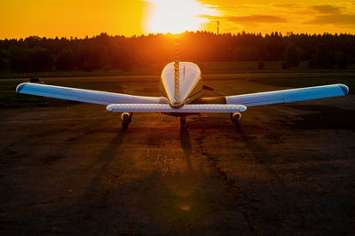 Airplane on airport runway against sky during sunset