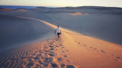 High angle view of man walking on sand dune in desert