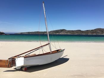 Sailboat moored on beach against sky