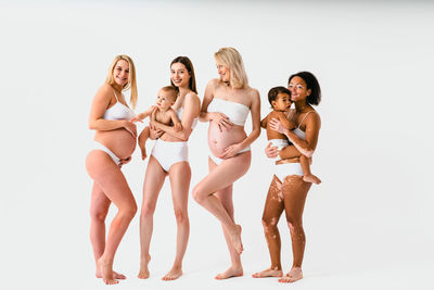 Side view of female friends standing against white background