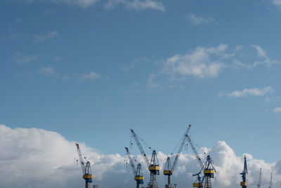 Low angle view of cranes at construction site against sky