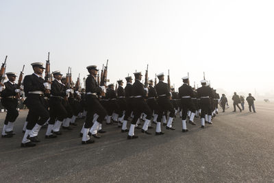 Army soldiers marching on road against sky