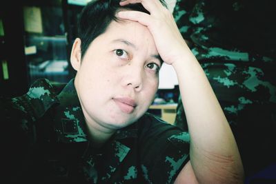 Close-up portrait of tensed female army soldier with head in hand