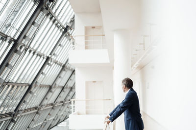 Senior businessman leaning on railing in corridor at office