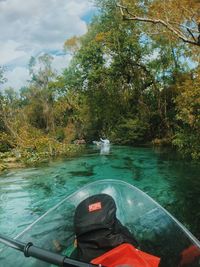 Man in boat by trees against sky