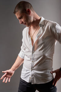 Young man looking away while standing against wall