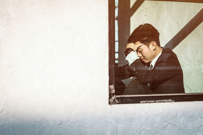 Young tensed businessman seen through window glass