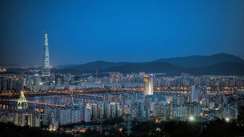 High angle shot of illuminated cityscape against blue sky